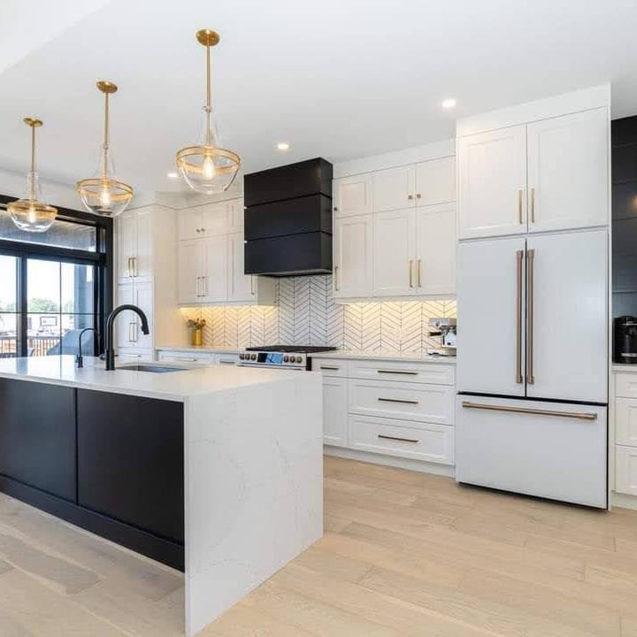White shaker kitchen with a black waterfall quartz island, brass pendants and a black range hood, renovated by Elm Kitchen