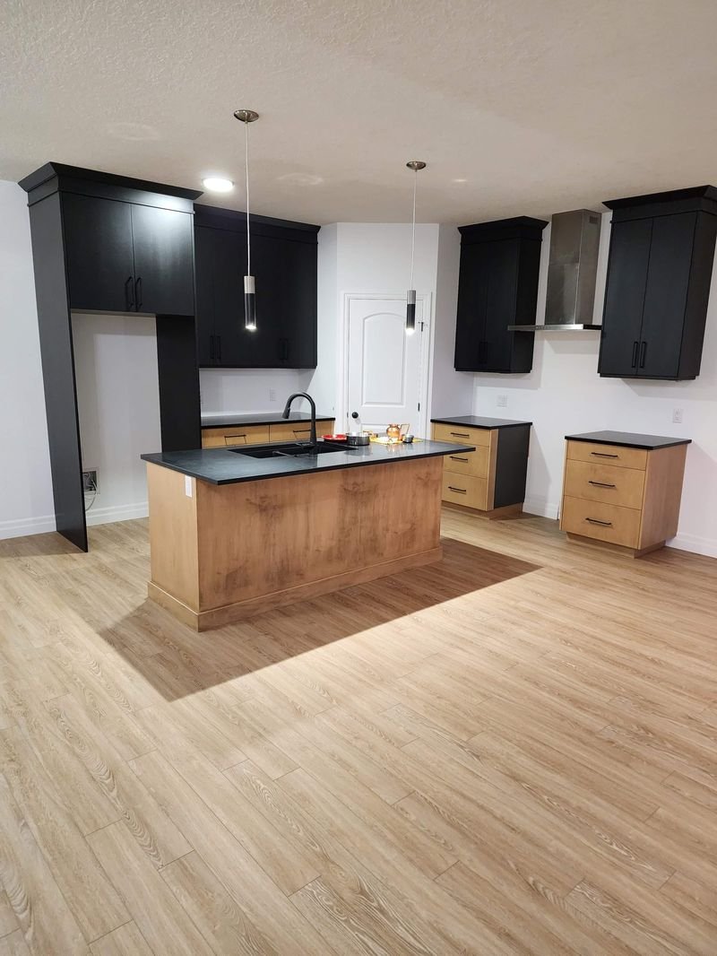 Open concept kitchen with a custom wood island, black cabinetry and LVP flooring, renovated by Elm Kitchen in Elgin County