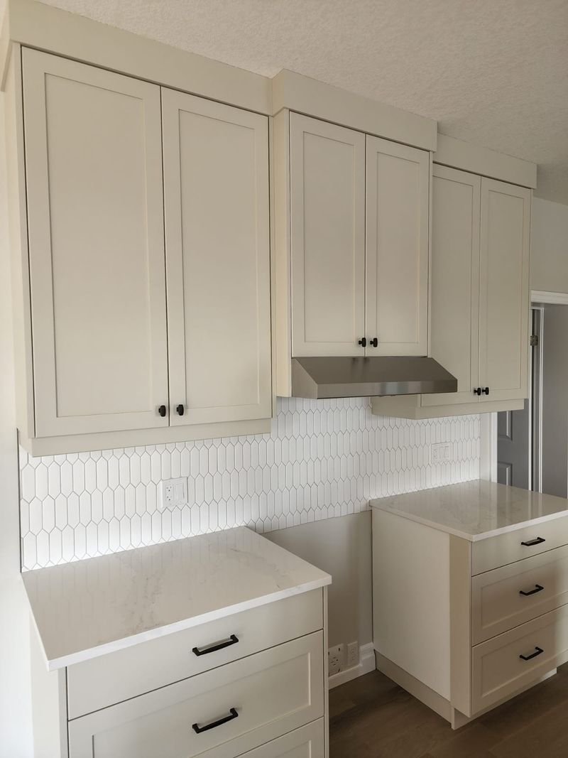 Ivory shaker cabinets with a picket tile backsplash and quartz countertops, installed by Elm Kitchen